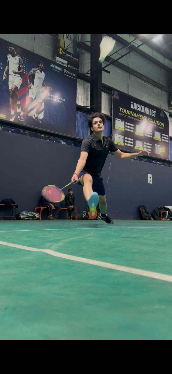Player lunging for a shot on a synthetic badminton court